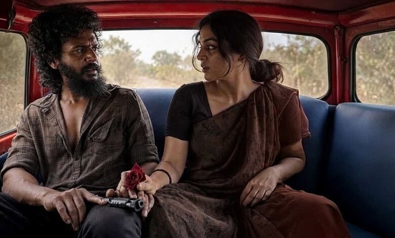 Two people sitting in a vehicle, engaged in conversation, with a rural landscape outside.