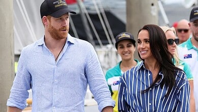Prince Harry and Meghan smiling and walking at the marina with friends and family.