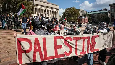 Pro-Palestine protesters holding a large Palestine banner during demonstration in Berlin.