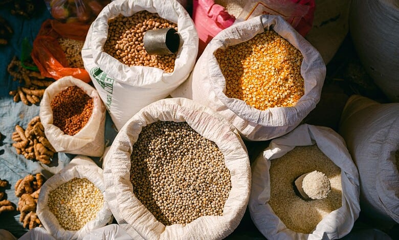 Colorful grains in sacks at a market stall, showcasing diverse types of pulses and cereals.