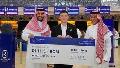 Three men holding a boarding pass at Riyadh Airport for the inaugural Riyadh to Mumbai flight.