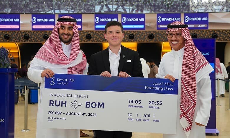 Three men holding a boarding pass at Riyadh Airport for the inaugural Riyadh to Mumbai flight.
