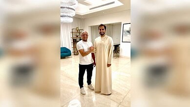 Roberto Carlos in traditional Islamic attire with a man in a modern living room setting.