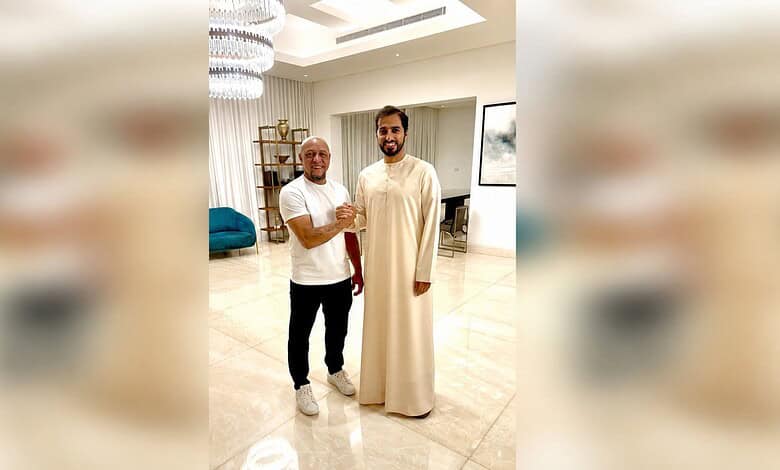 Roberto Carlos in traditional Islamic attire with a man in a modern living room setting.