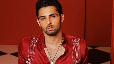Portrait of a young man in a red shirt with a serious expression.