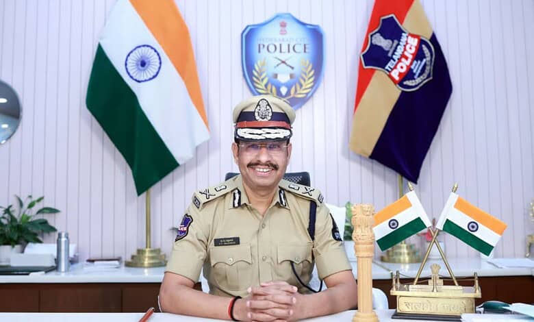 Hyderabad police chief Sajjanar smiling in his office with Indian flags and police emblems behind him.