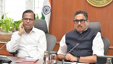 Two men in formal attire seated at a conference table during a meeting in Telangana