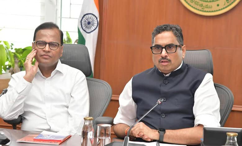 Two men in formal attire seated at a conference table during a meeting in Telangana