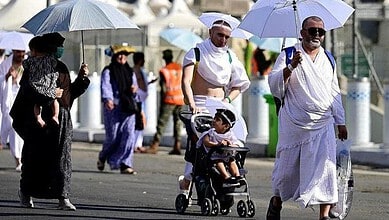 Pilgrims in Mecca using umbrellas to shield from the sun during Hajj.