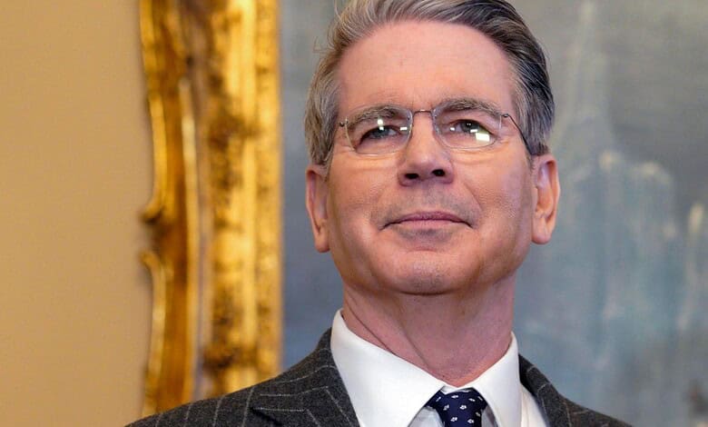 Bessent, a middle-aged man with glasses, in a formal suit, speaking at a diplomatic event.