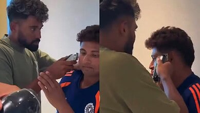 Mohammed Siraj giving a haircut to a young boy in a casual setting.