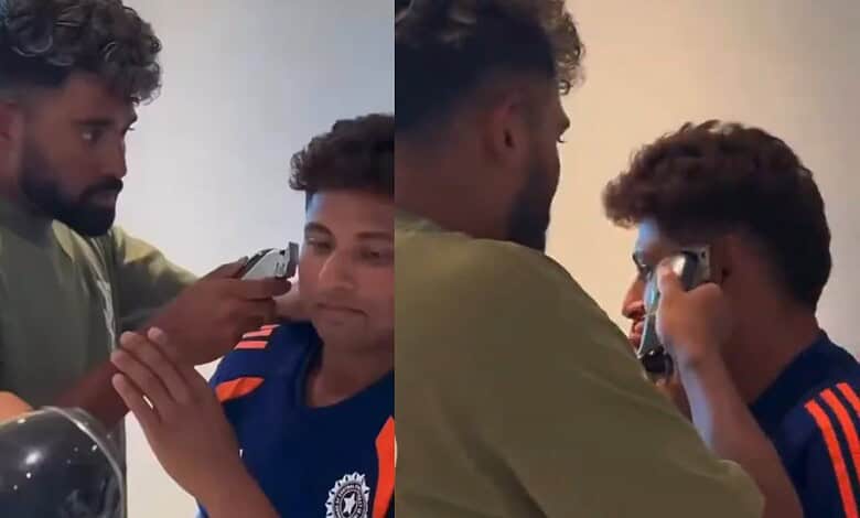 Mohammed Siraj giving a haircut to a young boy in a casual setting.