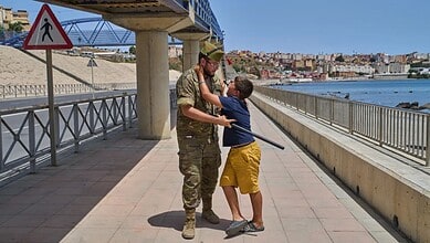 A 12-year-old unaccompanied minor who crossed into Spain is escorted by a Spanish soldier to the Spain-Morocco border as the child begs not to be sent back to Morocco from the Spanish enclave of Ceuta, Monday, Aug. 3, 2026. The forced deportation of the unaccompanied minor was stopped by a high-ranking official a few meters before the child reached the border after residents and journalists said the migrant was a minor. (AP Photo/Bernat Armangue)