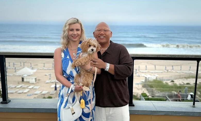 Happy couple with a dog on a balcony overlooking the beach in en_GB.