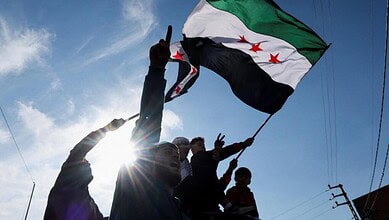 Group of people holding a Syrian flag during a demonstration against US sanctions.