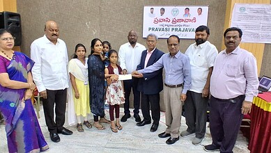 Group of people presenting aid to a young girl in a community event in Telangana.