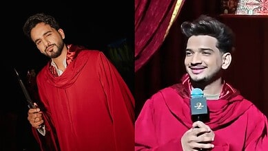 Two men in red robes, one holding a microphone, smiling on stage during a show.