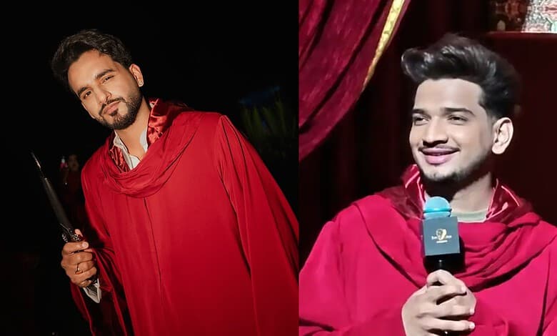 Two men in red robes, one holding a microphone, smiling on stage during a show.