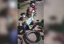 Man with a beard and traditional cap repairing a bicycle puncture outdoors.