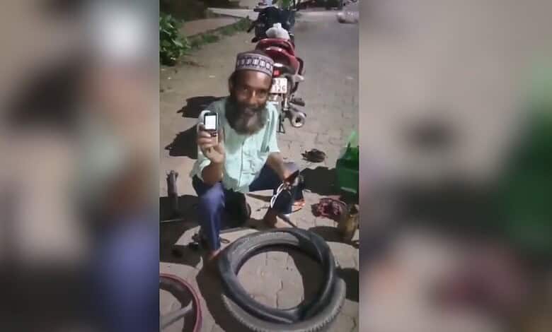 Man with a beard and traditional cap repairing a bicycle puncture outdoors.