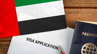 UAE visa application form with passport and flag on wooden surface.