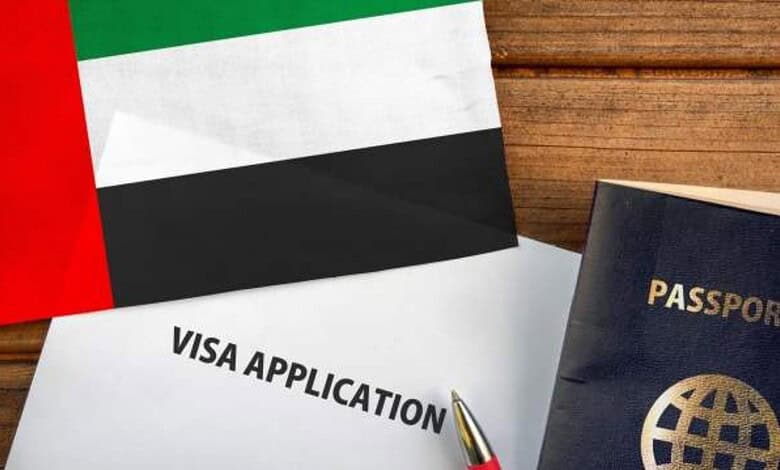 UAE visa application form with passport and flag on wooden surface.
