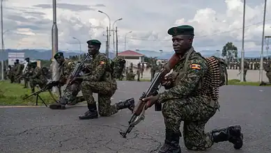 Ugandan soldiers kneel with rifles during a military deployment exercise, as parliament approves the country's participation in an international force planned for Gaza.
