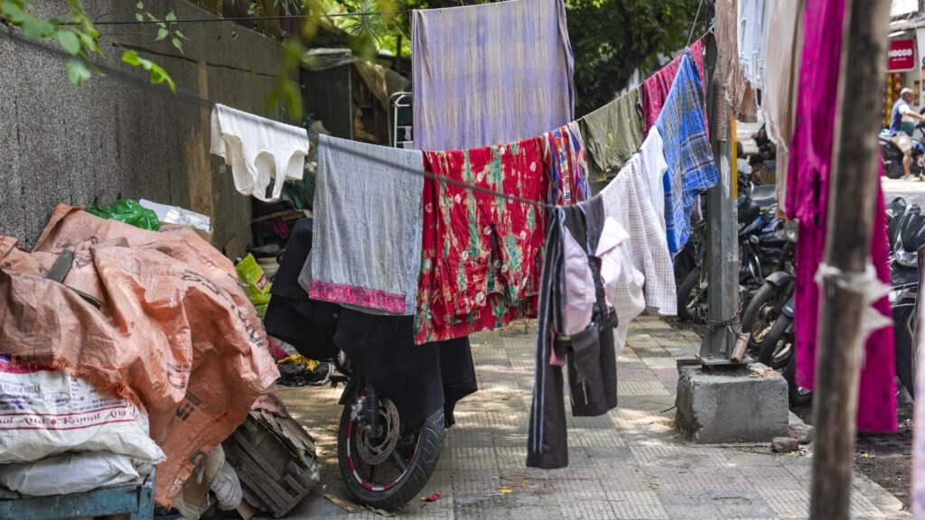 Clothes hanging on a line on a busy street sidewalk in India.