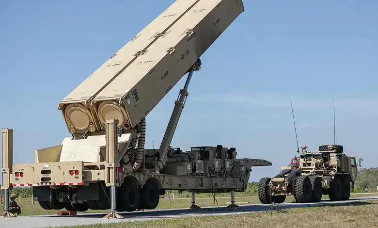 Military missile system being transported by truck on a highway with a support vehicle nearby.