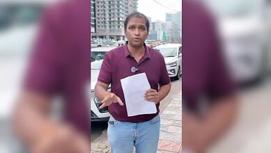 Woman holding a paper in an urban parking lot with high-rise buildings in the background.