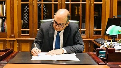Vipul signs documents at his desk.