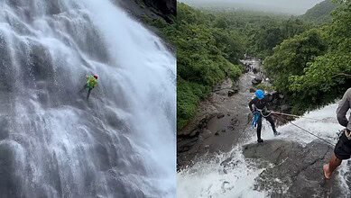 Two climbers exploring a waterfall and river in lush green forest landscape.