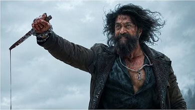 A rugged man with wild hair and beard holding a dagger, set against a cloudy sky.