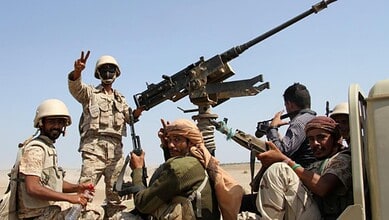 Yemeni soldiers with mounted artillery and weapons in a desert setting.