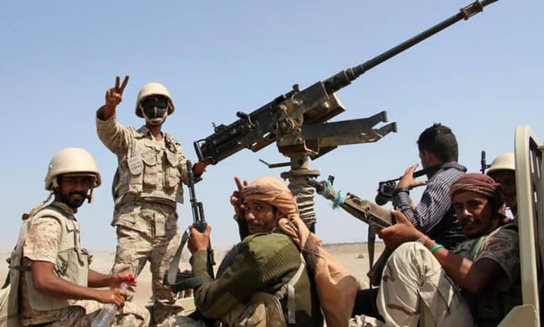 Yemeni soldiers with mounted artillery and weapons in a desert setting.