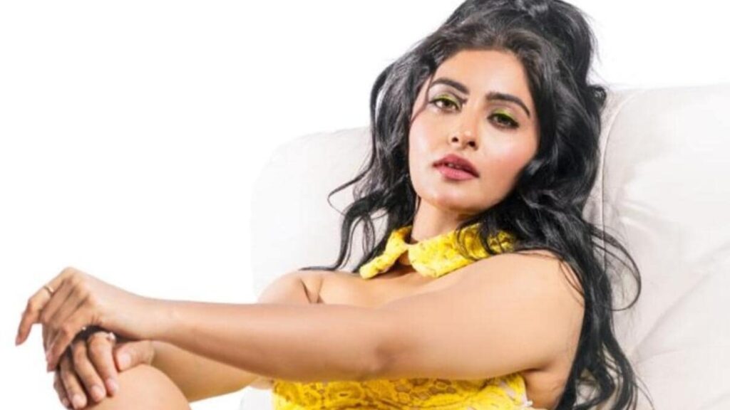 Stylish woman with dark hair and yellow dress posing on a white background.
