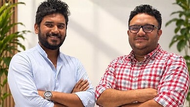 Two smiling men with crossed arms in an office setting, representing startup founders.