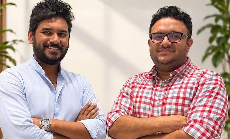 Two smiling men with crossed arms in an office setting, representing startup founders.