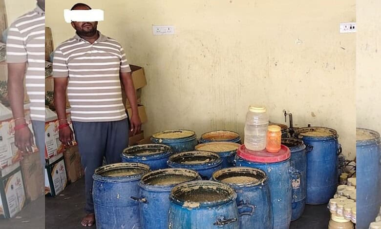Man standing near large blue containers of suspected adulterated ginger-garlic paste in a room.