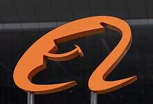 Orange question mark sculpture on a dark background, symbolising inquiry or curiosity.