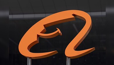 Orange question mark sculpture on a dark background, symbolising inquiry or curiosity.
