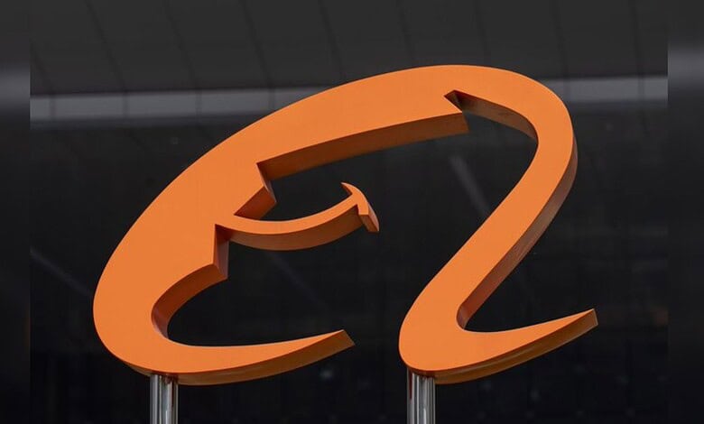 Orange question mark sculpture on a dark background, symbolising inquiry or curiosity.