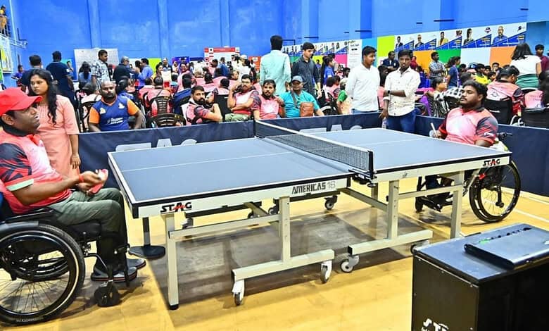 Wheelchair user playing table tennis at a busy indoor sports event in Hyderabad.