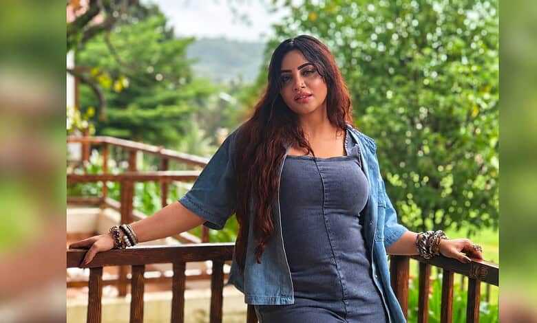 Arshi Khan posing outdoors with greenery in the background, wearing a denim jacket and top.
