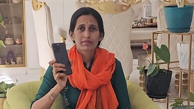Woman holding a smartphone in a well-decorated room with plants and ornaments.
