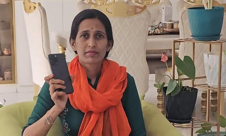 Woman holding a smartphone in a well-decorated room with plants and ornaments.
