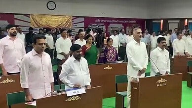 Politicians and officials stand during a formal event in a conference hall with green carpet.