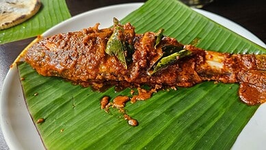 Spicy fish curry served on a banana leaf with rich, flavorful sauce.