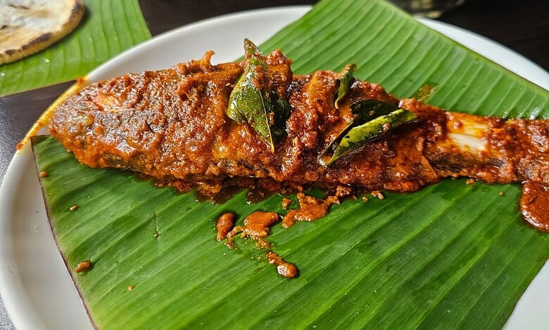 Spicy fish curry served on a banana leaf with rich, flavorful sauce.