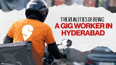 Gig worker in Hyderabad riding a motorcycle with a helmet and orange shirt.